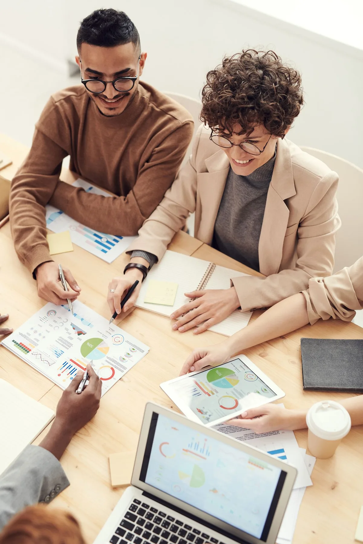 Professionals reviewing documents, charts and notes together at a meeting table.