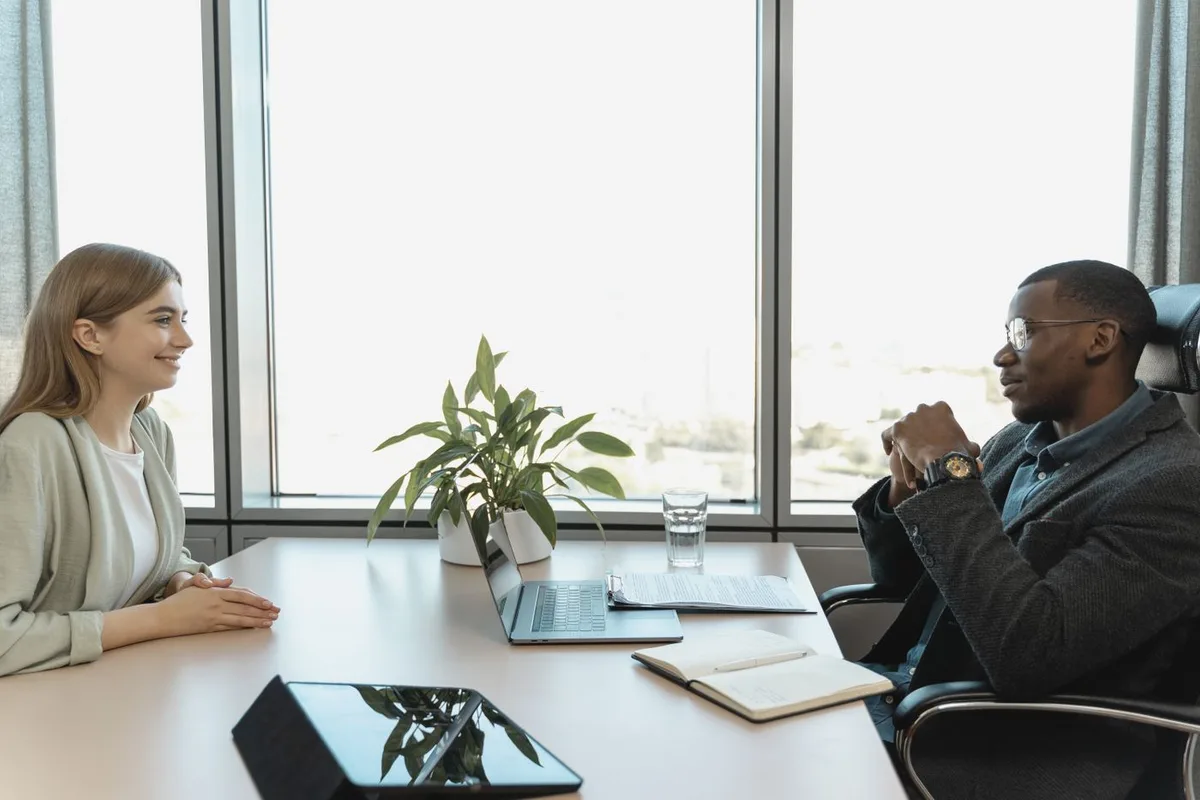 A candidate speaking with an interviewer across an office desk.